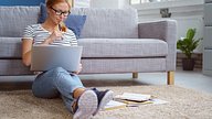 Young woman studying from home with her laptop and course books